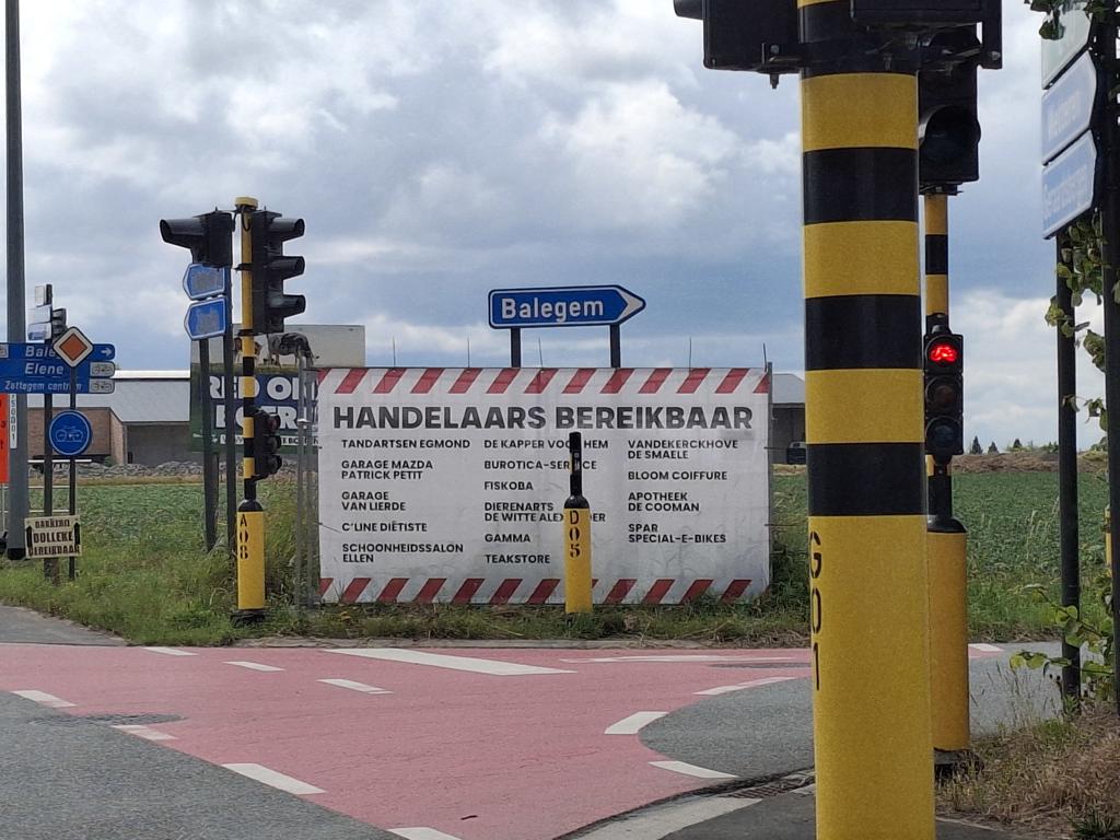 Foto van een doek aan een kruispunt, met daarop een oplijsten van de lokale handelaars die bereikbaar blijven tijdens de werken aan de N46 in Velzeke